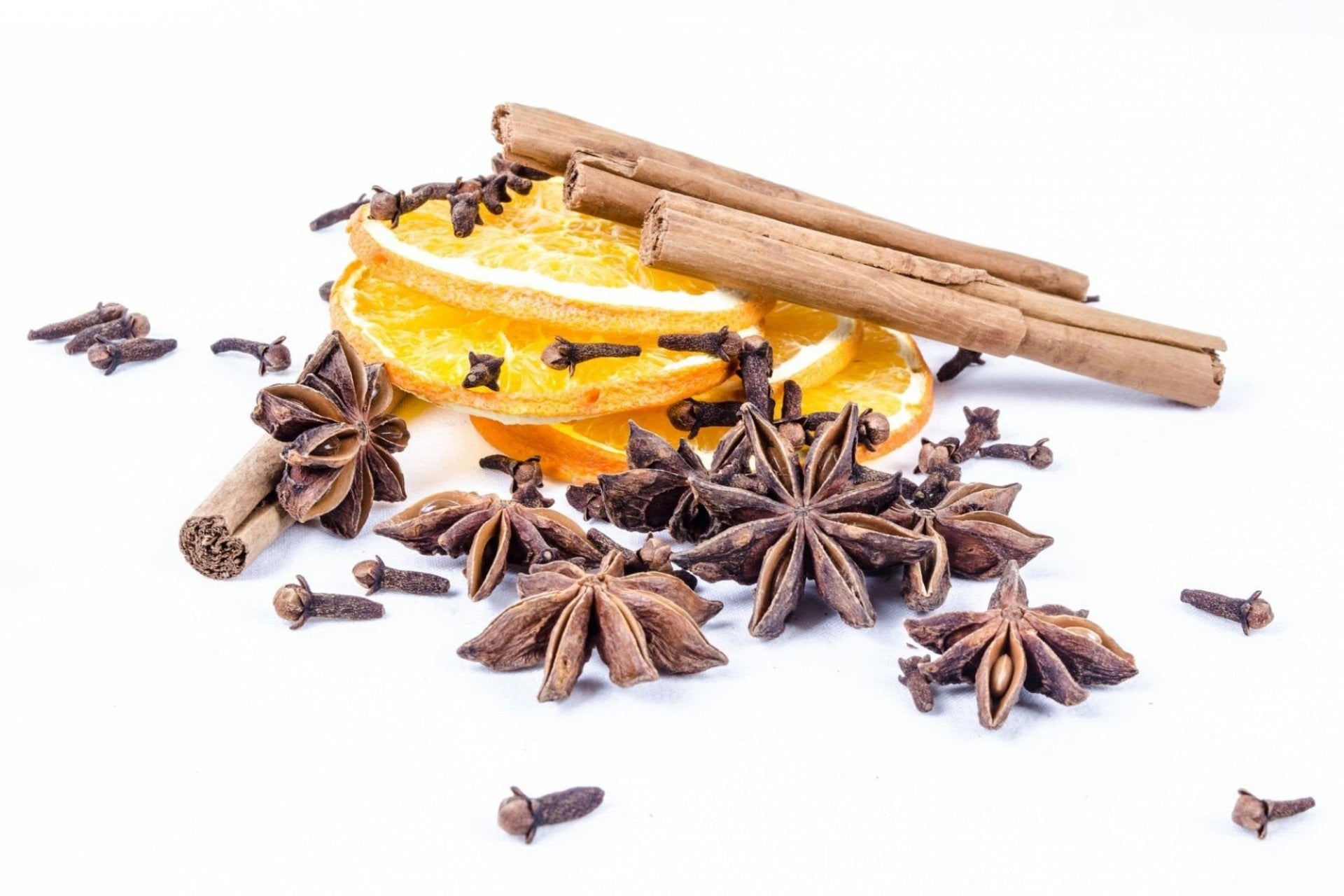 Spices including star anise, cinnamon sticks, and orange slices on a white background Perfume Oil, Body Spray